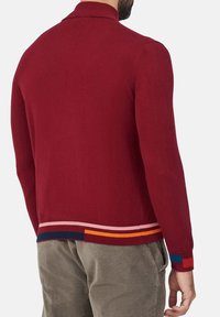 Giacca lavorata a maglia rossa con un colletto elegante, maniche lunghe e un orlo striato multicolore. Presenta una texture liscia e un design aderente.