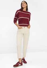 Burgundy-stribet sweater med bred halsudskæring, beige bukser og burgundy sneakers. Blød tekstur, afslappet pasform og cropped design.