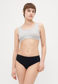 Harmaa puuvillainen bralette, jossa on kulma-kaula-aukko, yhdistetty mustiin korkeavyötäröisiin alushousuihin. Sujuva pinta, minimalistinen muotoilu, ei näkyviä kiinnityksiä.