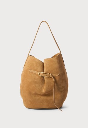 Suede-kankaiset ämpärilaukku vaaleanruskeana, jossa on taitto-design, kultasävyinen solki ja pitkä olkahihna. Pehmeä texture ja rakenteeltaan vapaamuotoinen.