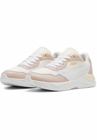 Baskets de sport blanches et rose clair en mesh et matériaux synthétiques, avec une semelle rembourrée, un laçage à l'avant et des accents de marque discrets.