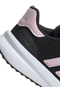 Schwarzer Sportschuh mit einer strukturierten Mesh-Oberfläche, rosa Akzenten an Ferse und Logo sowie einer weißen Cloudfoam-Zwischensohle und einer profilierten Außensohle.