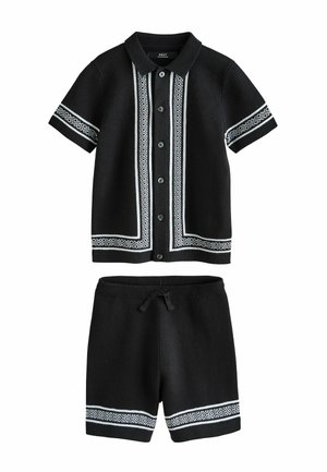Schwarzes kurzärmeliges Hemd mit Knöpfen und Kragen sowie passend dazu kurze Hosen, beide mit weißem geometrischem Muster an den Kanten und Bündchen versehen.