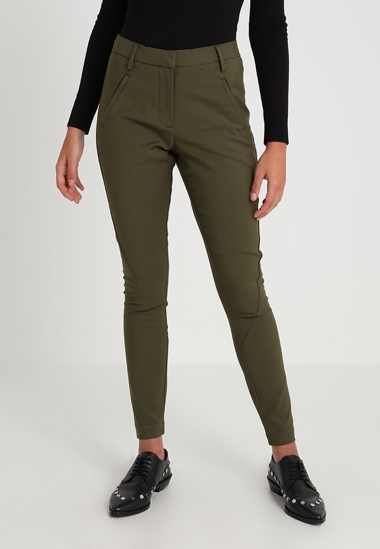 Olivgrön slim-fit byxor i ett smidigt tyg, med framfickor och hög midja, parat med svarta nitar skor.