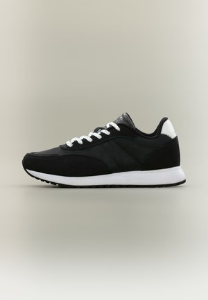 Baskets basses noir et blanc avec lacets et semelle blancs, présentées de côté sur un fond neutre uni.