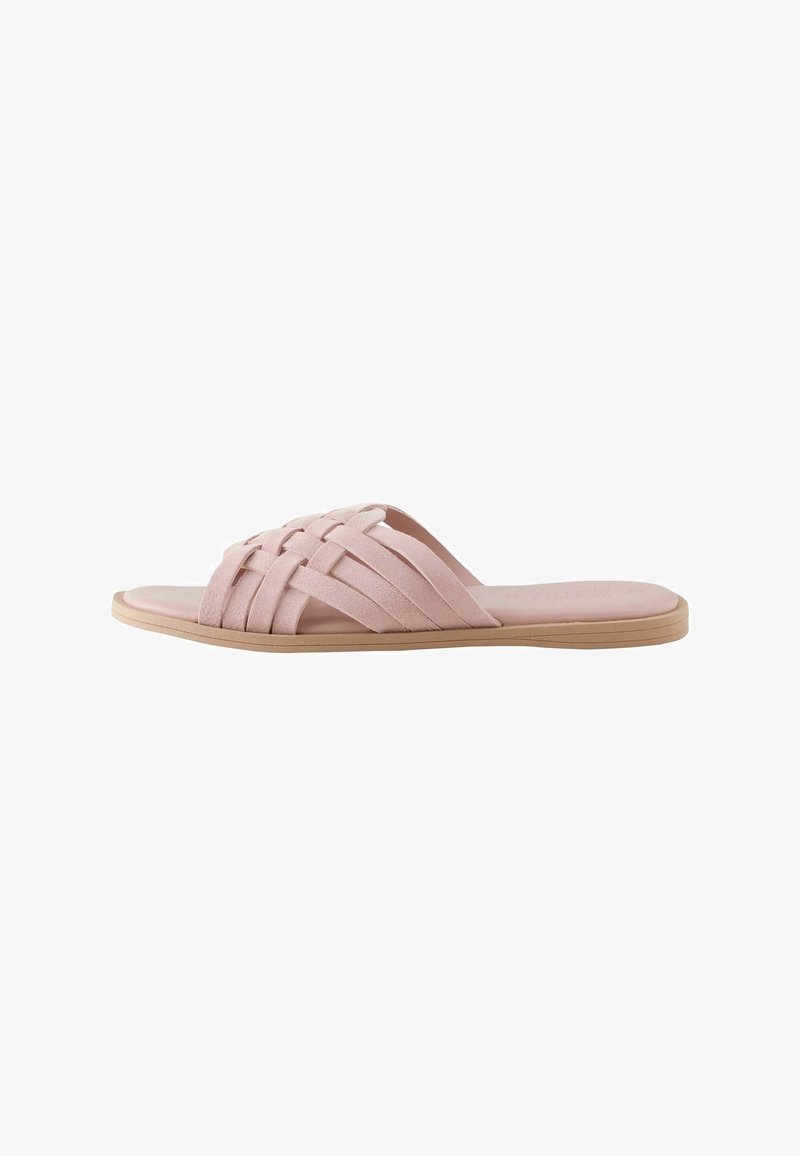 Sandale plate rose clair avec brides en daim tressé et semelle beige.