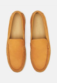 Smeđe kožne cipele na slip-on, meke teksture, s ušivenim dizajnom na prednjem dijelu i svijetlim tkanim potplatom.