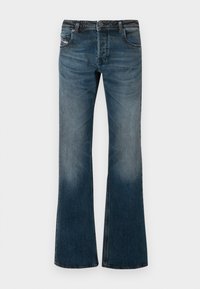 Calças de ganga azuis desbotadas com um design de perna flare, cinco bolsos e uma cintura escura. Apresentam desgaste suave nas coxas.