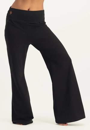 Schwarze Yoga-Hosen mit breitem Taillenbund und ausgestellten Beinen. Weicher Stoff mit subtiler Textur und kleinem Logo-Detail am Taillenbund.