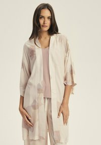 Lekki, kremowy kimono z delikatnym kwiatowym wzorem w jasnym różu i beżu. Rękawy o średniej długości i otwarty krój z przodu. Połączony z pasującym topem.