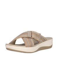 Beige kudottu liukusandaali, jossa on säädettävä hihna, pyöreä avokärkinen muoto ja valkoinen pehmustettu pohja, jossa on hienovarainen muotoilu ja pito-tekstuuri.