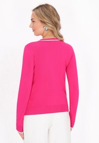 Fuchsia-pinker Pullover mit langen Ärmeln, geripptem Saum und einem weißen Akzent am Kragen, gefertigt aus einem glatten, dehnbaren Stoff.