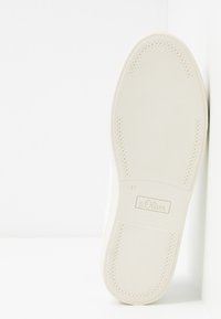 Weiße Gummisohle mit strukturiertem Grip, versehen mit einem Logo und einer Größenprägung. Einfaches Design mit leichter Krümmung und perforierten Details.