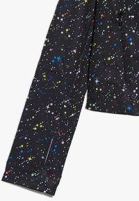 Schwarzer Jackenärmel mit einem mehrfarbigen, weltraumthemen Muster aus Punkten und Sternen, hergestellt aus strukturiertem Stoff und inklusive einer Reißverschlusstasche.