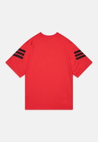 Rotes Baumwoll-T-Shirt mit Raglanärmeln. Verfügt über drei schwarze Streifen auf jeder Schulter. Glatte Textur, lässige Passform und runder Ausschnitt.