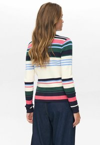 Večbarvni prugasti pulover z ribasto teksturo, ki vsebuje trakove mornarsko modre, roza, zelene in modre barve na kremnem ozadju. Oblika je prilegajoča, z dolgimi rokavi.