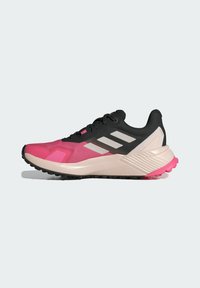 Zapatilla deportiva en color rosa y negro con parte superior texturizada, que presenta tres franjas blancas y una suela gruesa con acentos rosas.