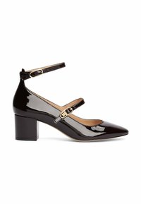 Zapatos de tacón alto de charol negro con punta afilada, correas al tobillo y tacón cuadrado. Incluye hebillas en tono dorado en las correas.
