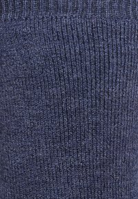 Tissu tricoté bleu marine avec une texture côtelée, présentant une surface douce et légèrement duveteuse ainsi que des lignes verticales uniformément espacées.