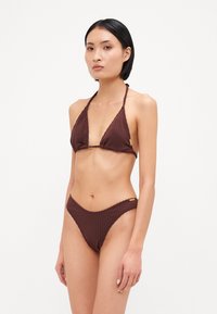 Brun ribbet bikinitrøye med halterneck og tvistet detaljer, samt matchende lavtsittende bunn med en subtil gullak accent.