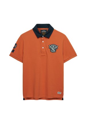 Oranje polo met korte mouwen en een marineblauwe kraag, drie witte knopen, geborduurd embleem op de linkerborst en gedetailleerde patches op de linker mouw en zoom.