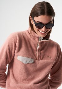 Rosa Fleece-Pullover mit hohem Kragen, Knopfleiste und einer hellgrauen Brusttasche. Besitzt strukturierten Stoff und ein minimalistisches Logodesign.