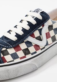 Sneaker kuviollaan ruudullinen, tummansininen pimennysnauha, valkoiset nauhat, valkoinen kumipohja sekä erottuva sivuraidat.