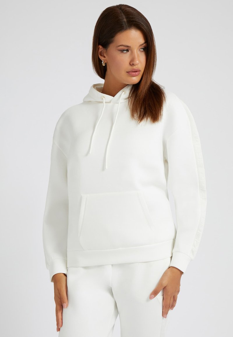 Vit hoodie med justerbar dragsko, känguruficka och texturerade sidodekorer. Mjuk tygkvalitet med långa ärmar och ribbad mudd.