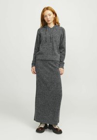 Hoodie grigio scuro con una finitura testurizzata, dotato di una tasca a marsupio sul davanti. Abbinato a una gonna lunga che tocca il pavimento realizzata nello stesso materiale.