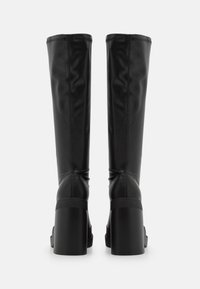 Bottes noires hautes jusqu'au genou en matériau synthétique lisse, avec un talon épais et des coutures visibles le long des coutures.