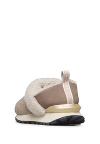 Ljusbruna slip-on sneakers med en mjuk shearlingkrage, guldaccent på hälen och en texturerad, flexibel gummisula.