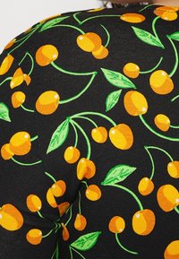 Tissu noir avec un motif de cerises orange vif et de feuilles vertes dispersées sur la surface.