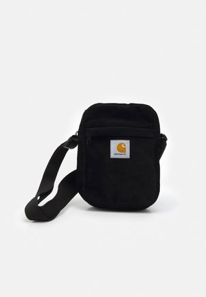 Lille sort Carhartt skuldertaske med justerbar rem og frontlomme med lynlås, med hvid patch-logo, på hvid baggrund.