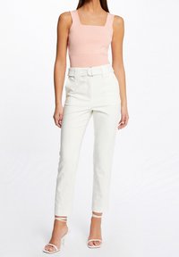 Top corto ribbed rosa con scollo quadrato abbinato a pantaloni bianchi a vita alta e diritti, con sandali bianchi con cinturini.