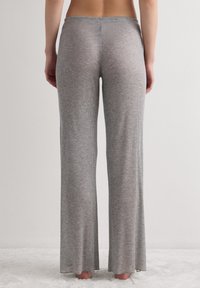 Šedé žebrované pletené kalhoty s rozšířeným střihem, které mají jemný, strukturovaný povrch a elastický pas. Bez viditelných kování a vzorů.