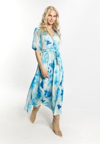Abito lungo e fluente in blu e bianco con motivo floreale acquerello, maniche corte a sbuffo, dettaglio con bottoni e vita con cintura.
