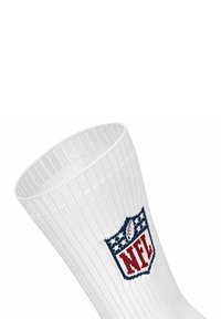 Hvide atletiksokker med ribbet tekstur, der har et rødt og blåt NFL-logo på den øverste del. Glat stof med en tætsiddende form.