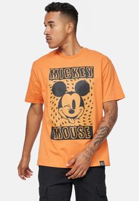 Oranžové bavlněné tričko s černou grafikou Mickey Mouse a textem "MICKEY MOUSE", s volným střihem a krátkými rukávy.