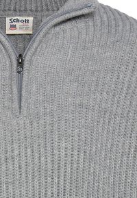Maglione grigio con cerniera a zip, caratterizzato da una trama a coste, con collo alto e una sottile lucentezza. Include un'etichetta con il marchio vicino alla cerniera.
