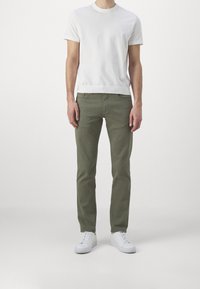 Biała koszulka z krótkim rękawem, oliwkowe spodnie, slim fit. Białe trampki. Minimalistyczny design, gładka faktura, styl casual.