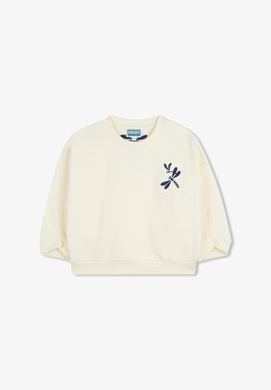 Sweatshirt crème clair avec col rond et coupe courte. Présente une broderie de libellule bleue marine sur le côté gauche et des poignets côtelés.