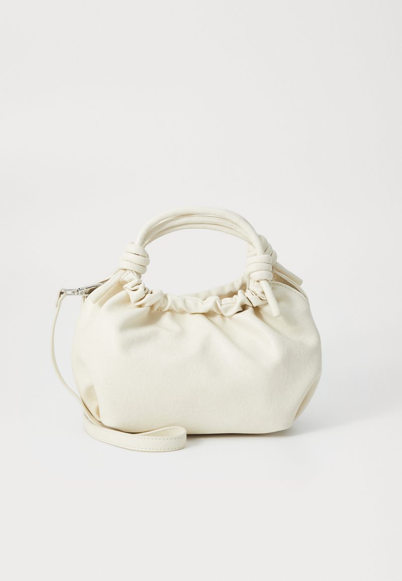 Bolsa de mão de cor creme feita de tecido macio, com um topo franzido, alça arredondada e uma alça destacável. Textura suave com hardware mínimo.