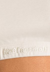 O tecido branco em relevo com uma textura suave apresenta um logo bordado "H2OFagerholt" em fio claro ao longo da borda inferior.
