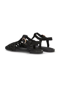 Sandalias negras trenzadas con un diseño abierto, que presentan una puntera redondeada, correas texturizadas y un acento de hebilla metálica. Suela plana.