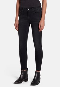 Black skinny jeans made of denim, featuring five pockets, front button closure, and a smooth texture. Pairing with black ankle boots.