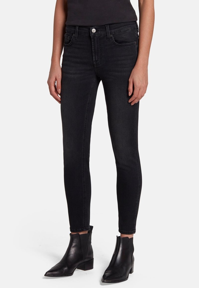 Black skinny jeans made of denim, featuring five pockets, front button closure, and a smooth texture. Pairing with black ankle boots.