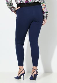 Námořnické legíny s hladkým texturem a elastickým pasem, spárované s lodičkami na vysokém podpatku se špičatou špičkou a kotníkovým páskem.