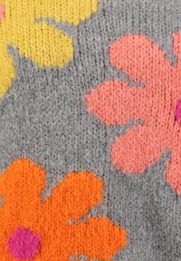 Strickstoff mit großen Blumenmustern in Orange, Pink und Gelb auf grauem Hintergrund, mit einer weichen, strukturierten Oberfläche.