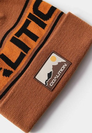 Brązowa dzianinowa czapka z wywiniętym mankietem, zdobiona pomarańczowym i czarnym graficznym wzorem oraz prostokątną naszywką z logo przedstawiającą góry i słońce.
