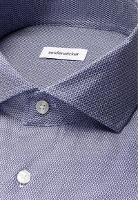 Camicia con bottoni, caratterizzata da un motivo circolare blu e bianco, con colletto classico, due bottoni e etichetta Seidensticker. Tessuto liscio.